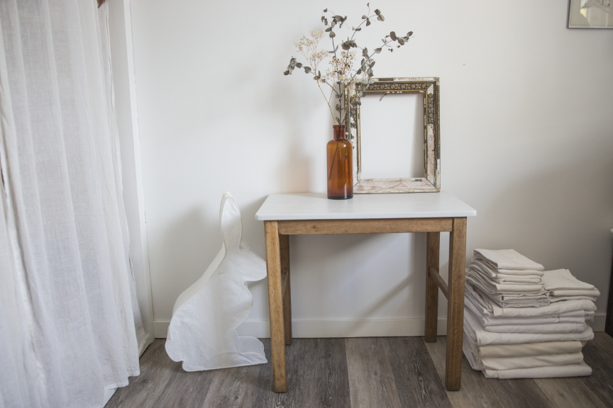 Bureau d'enfant ou table d'appoint en bois dont le plateau a été peint dans un gris clair. Tissus anciens, lapin lumineux, bouquet d'eucalyptus dans un vase en ambre