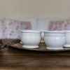 Petits pots en terre cuite émaillés en blanc artisanalement sur un plateau en bronze marocain sur une table en bois et avec de l'eucalyptus