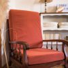 Fauteuil de couleur terracotta vintage en bois foncé. Présenté avec des herbes de la pampa, un meuble en bois blanc et des livres. Cosy time