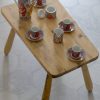 Service à café japonais rouge et doré avec un pot à lait six tasses une théière sur une table en bois brut clair et carrelage gris hexagonal