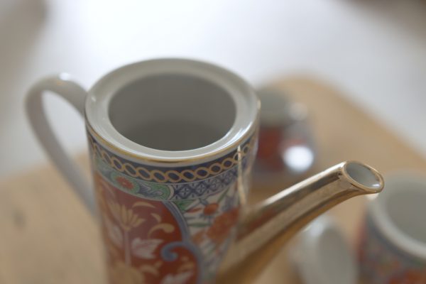 Service à café japonais rouge et doré avec un pot à lait six tasses une théière sur une table en bois brut clair