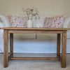 Table en bois brut rénovée vintage poncée et vernie. Canapé blanc, malle ancienne, corail et fleurs séchées dans un pot à moutarde en grès ancien