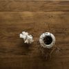 Table en bois brut rénovée vintage poncée et vernie. Canapé blanc, malle ancienne, corail et fleurs séchées dans un pot à moutarde en grès